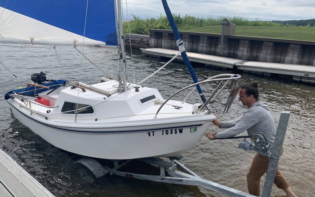 Bill Burrell loads his sailboat into Lake Champlain