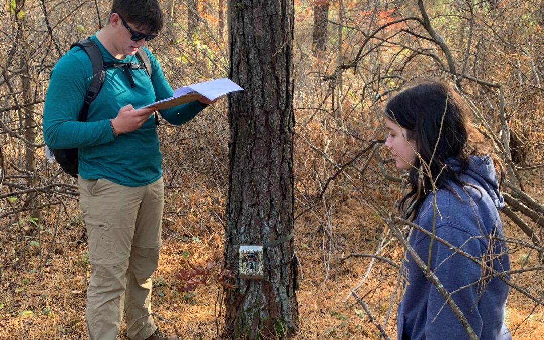 Environmental science students Lowell Nugent and Madeline McQuillen Slocombe interpret data from a trail camera